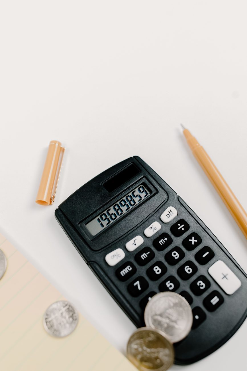 A calculator, coins and a pen laid out to work out a clear, fixed plumbing quote